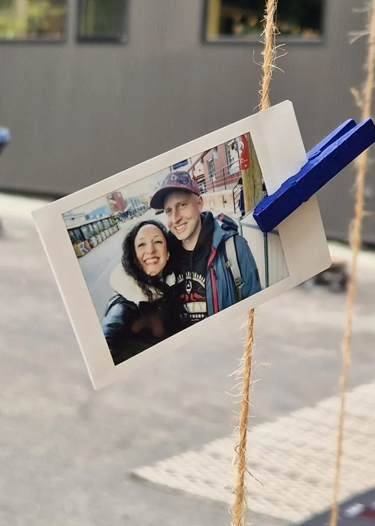 A printed photo of Ethan and Bahareh smiling together on the Salt Spring waterfront, clipped to a rope with a blue clothespin
